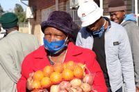 A woman receives oranges at an E1 F1 food distribution at Bodibe