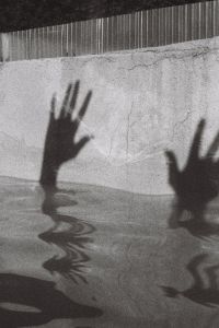 Shadow of hands on the edge of a swimming pool